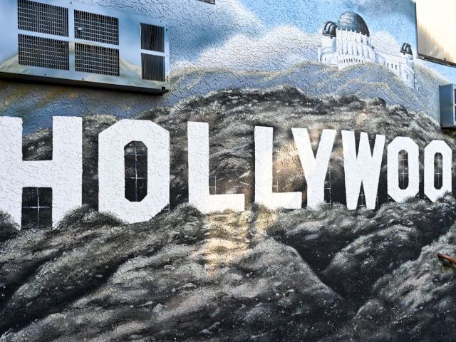 A mural on a building exterior featuring the word 'HOLLYWOOD' and an image of a famous observatory.