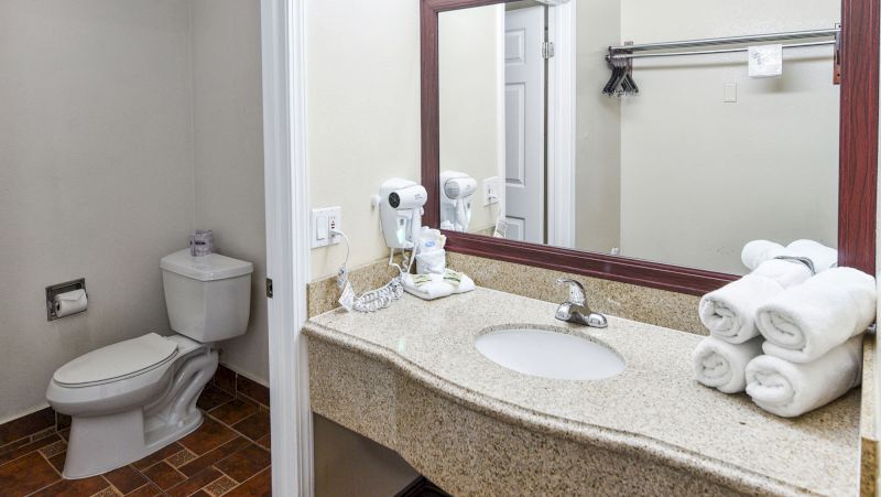 A hotel bathroom with a toilet, sink, and towels.