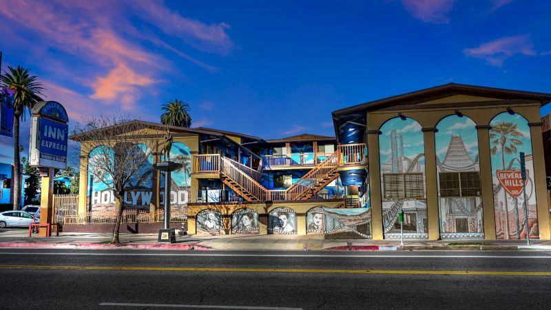 A colorful exterior of a hotel with murals, balconies, and a sign.